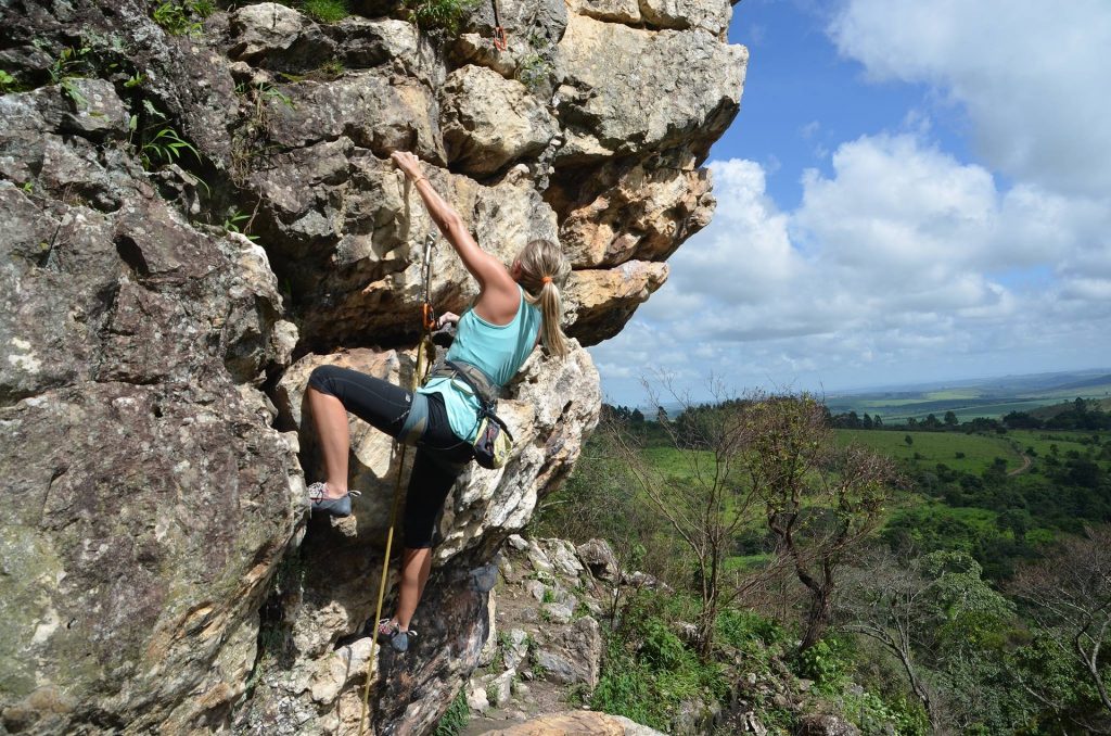 Eine Kletterin in der Natur - im Hintergrund blauer Himmel mit weißen Wolken