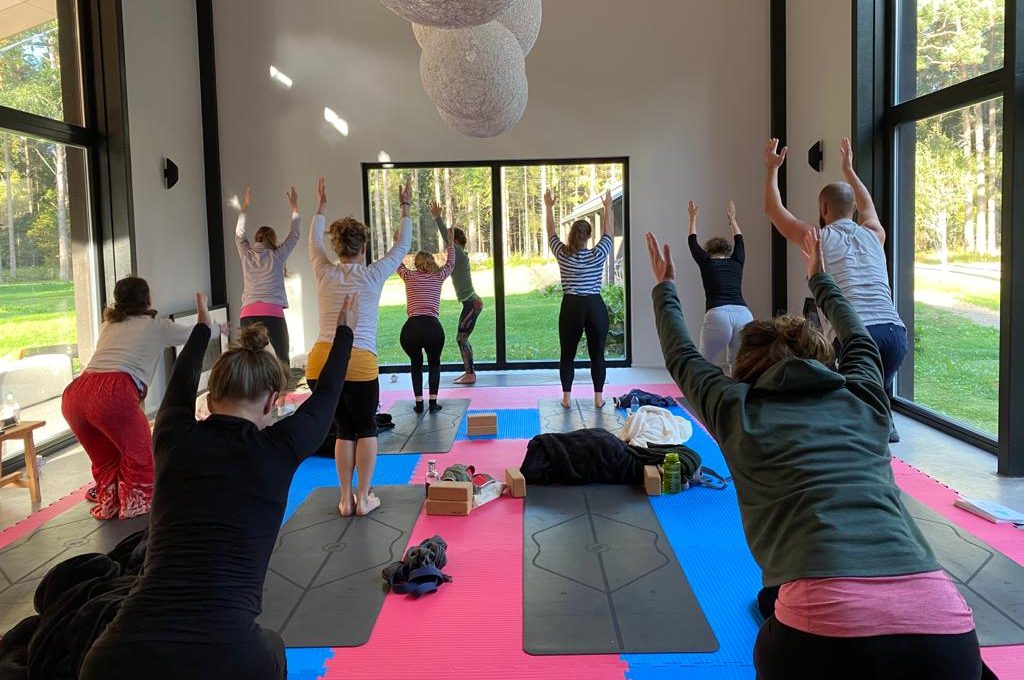 Eine Gruppe Menschen praktiziert Yoga in einem Raum mit Glaswänden